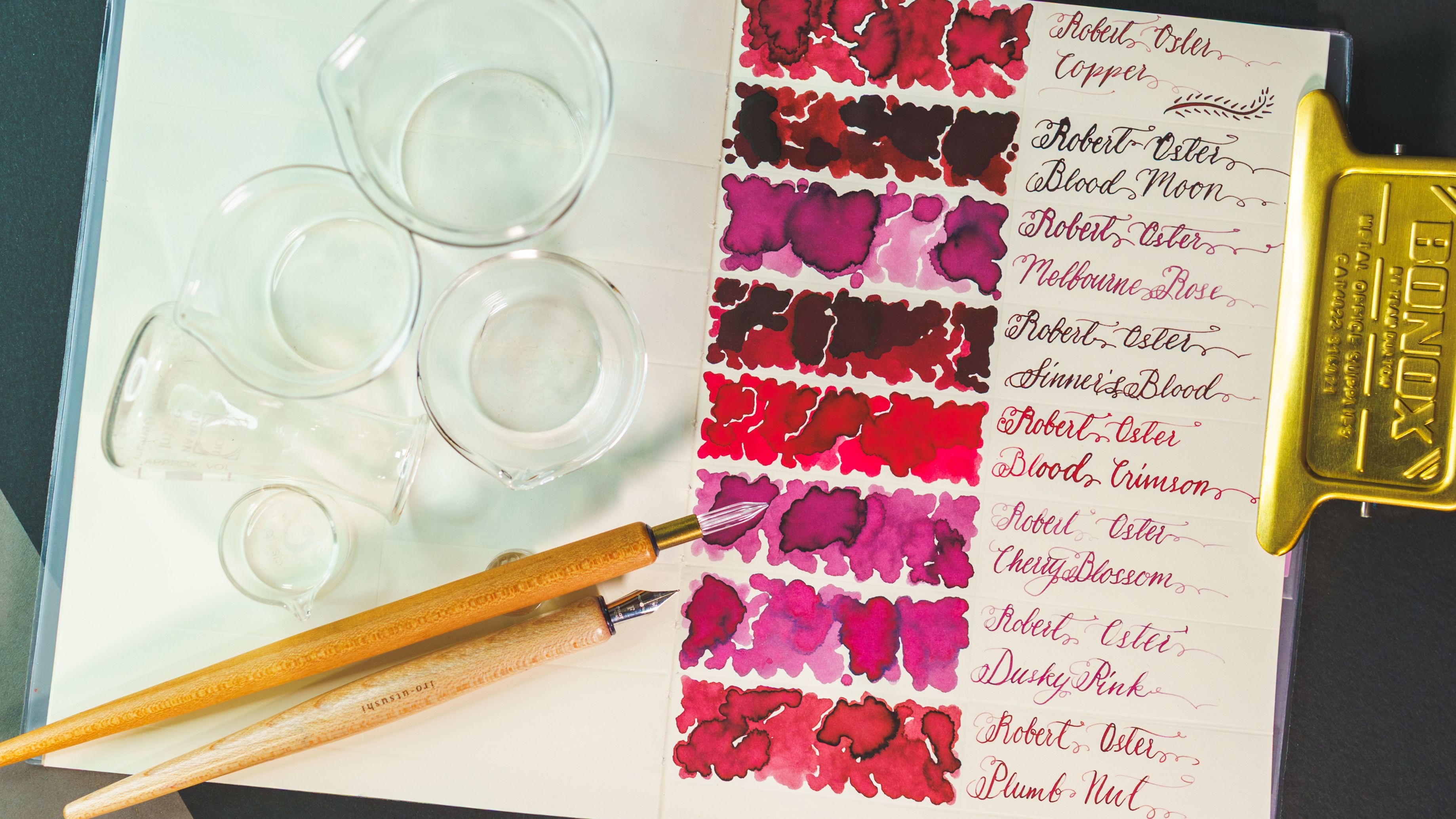 Robert Oster red ink swatches, dip pens, and novelty size glass labware containers