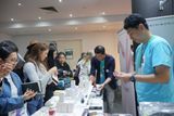 An exhibitor checks a pen amid a crowd of visitors at their table