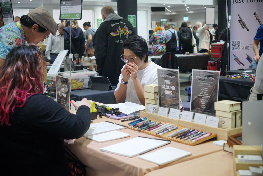 Daniel Zhang inspects a nib with a loupe at his table