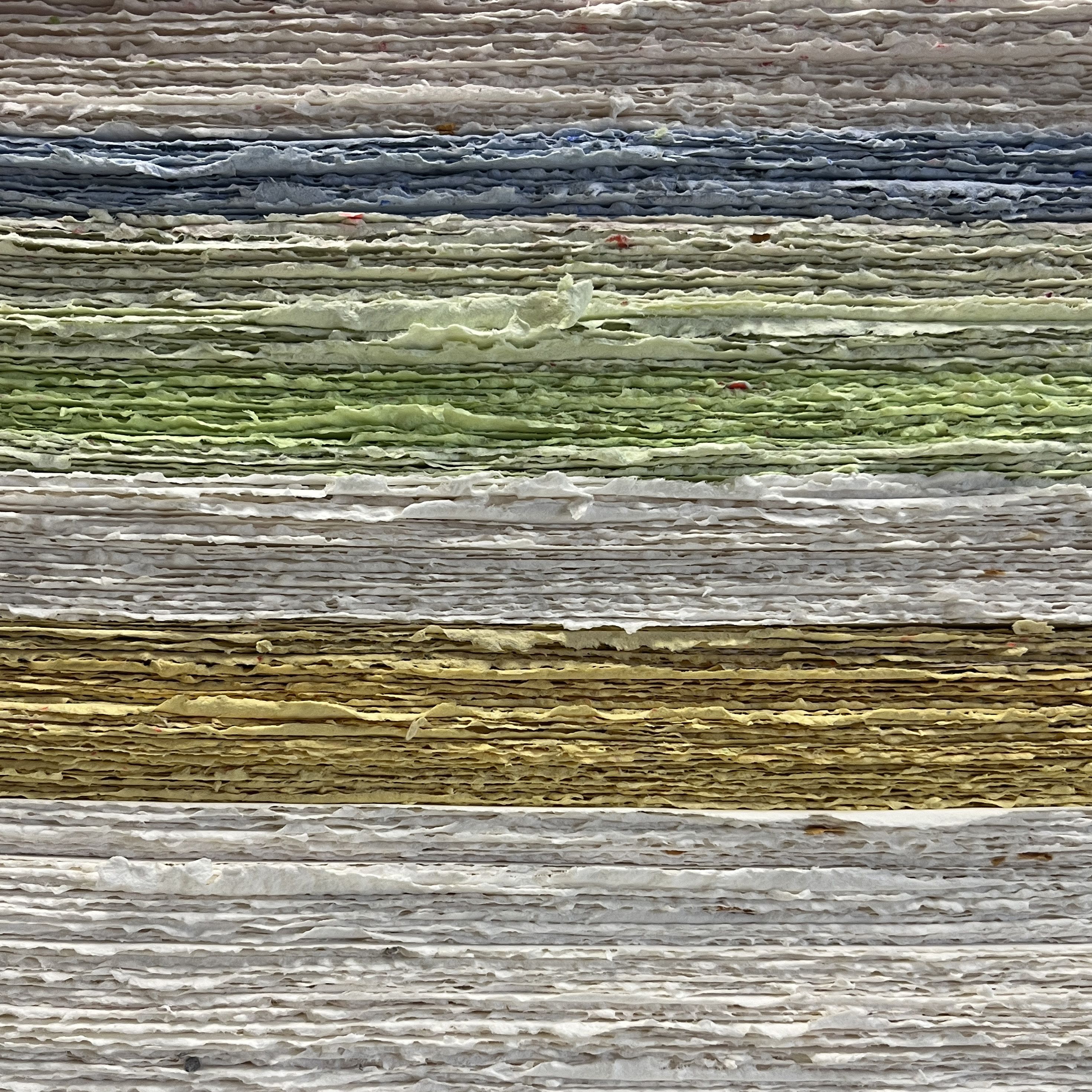 Raw side edge of a stack of colourful recycled paper