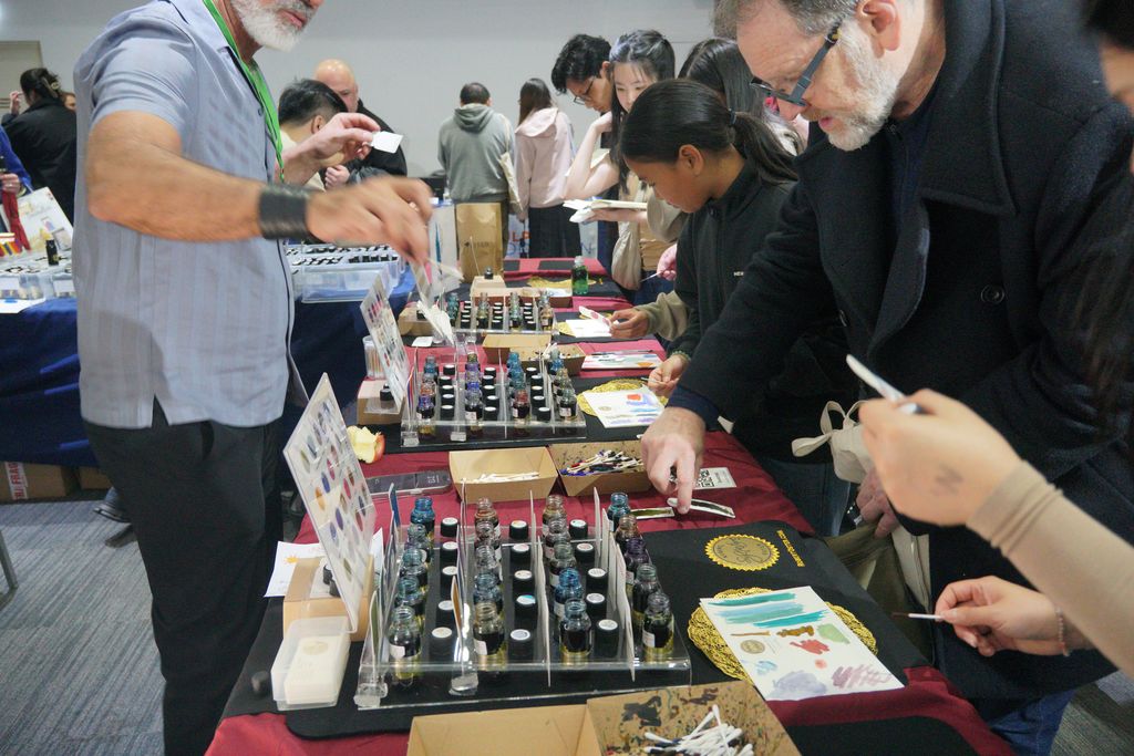 Visitors look at the open ink bottles and compare swatch cards