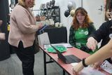 A happy guest and a volunteer in a green apron at the Info desk