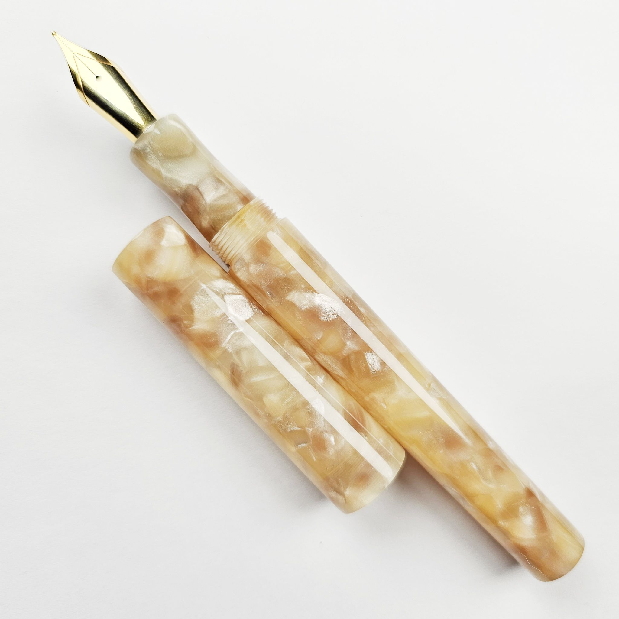 a hand-turned pen in glossy resin with an intricate yellow, beige, and tan pattern