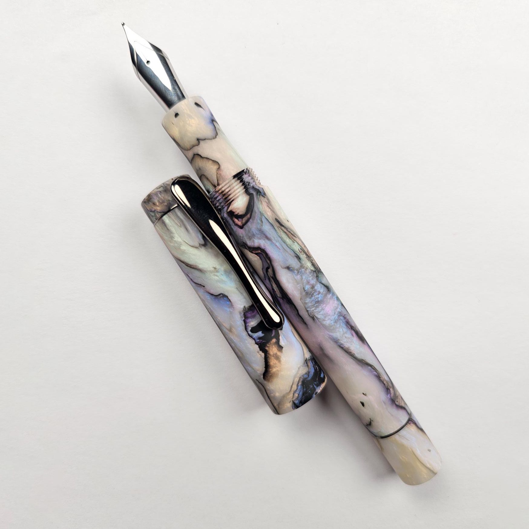 a hand-turned pen in glossy resin with an intricate black, purple, and white pattern