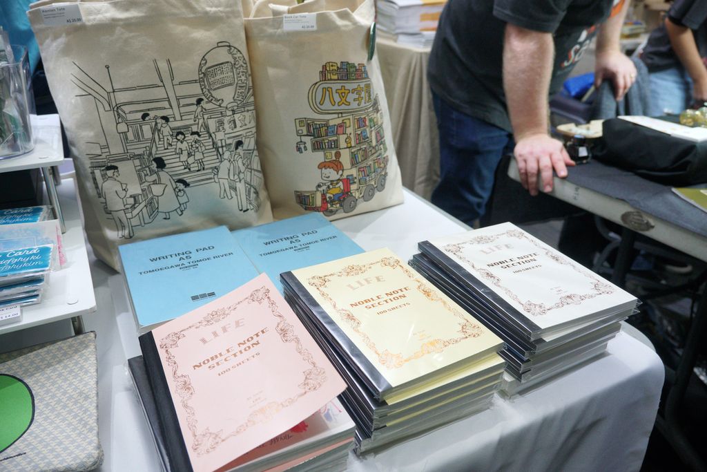 Stacks of Life notebooks in pink, yellow and blue covers