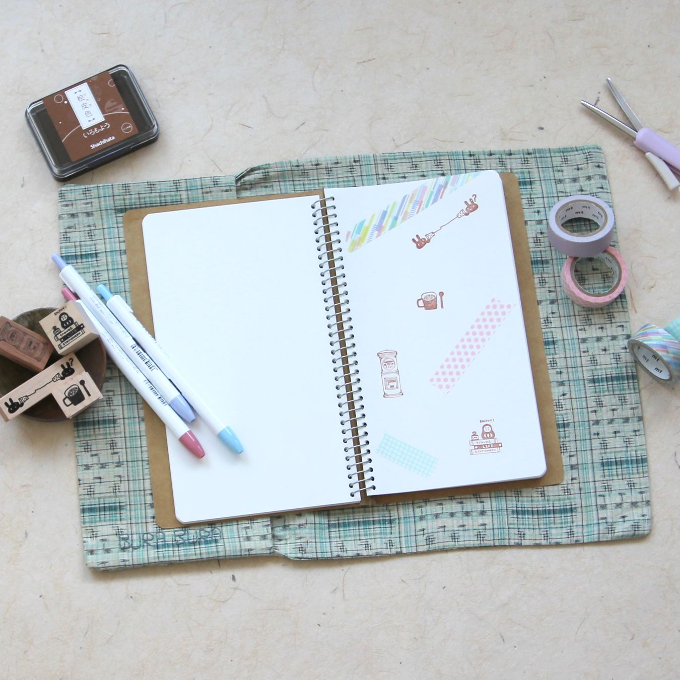 Journal and stationery items open on a green patterned recycled kimono journal wrap