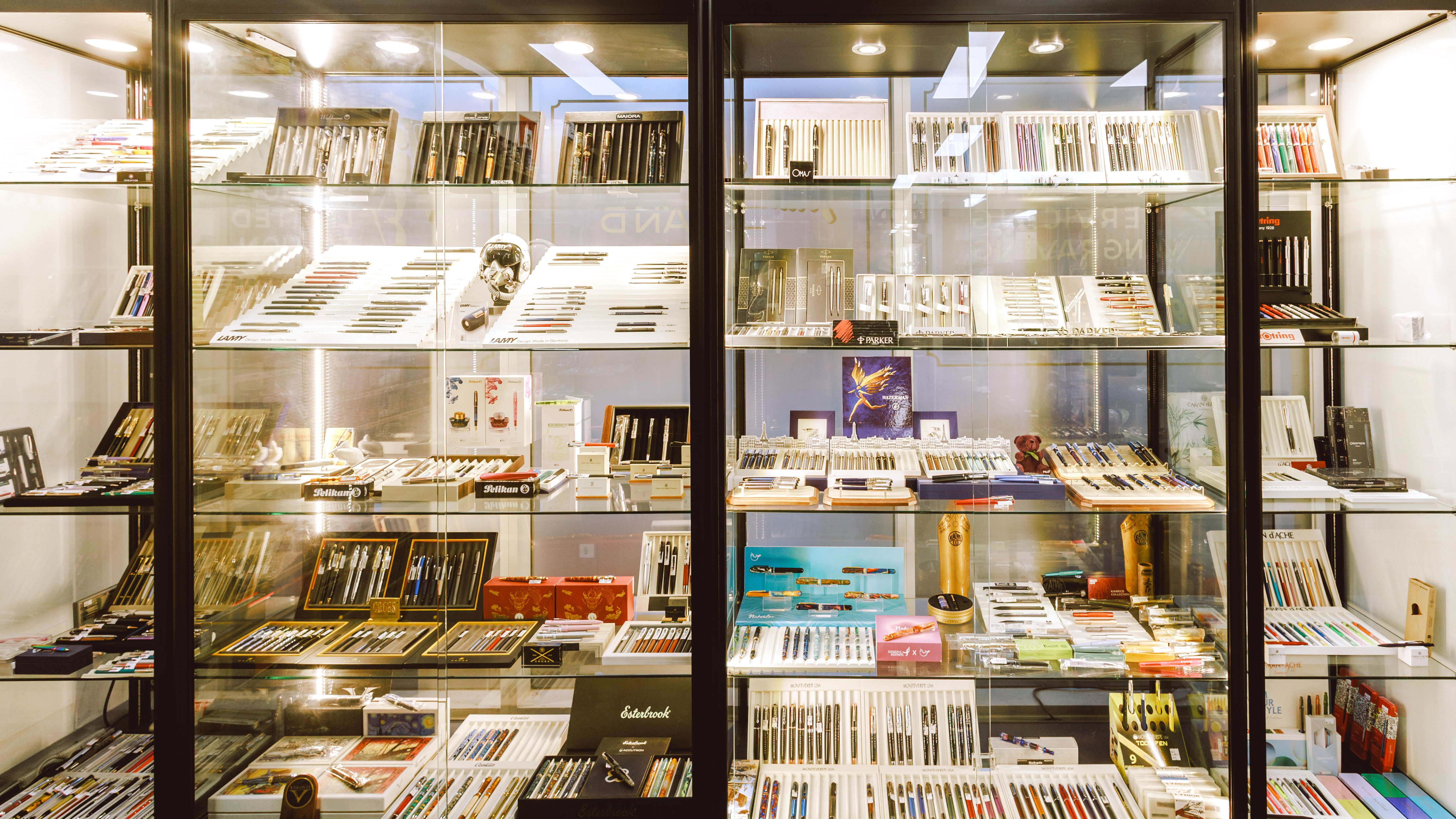 Glass display case containing a variety of pens and accessories