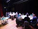 Workshop participants work around large, round tables up on the stage