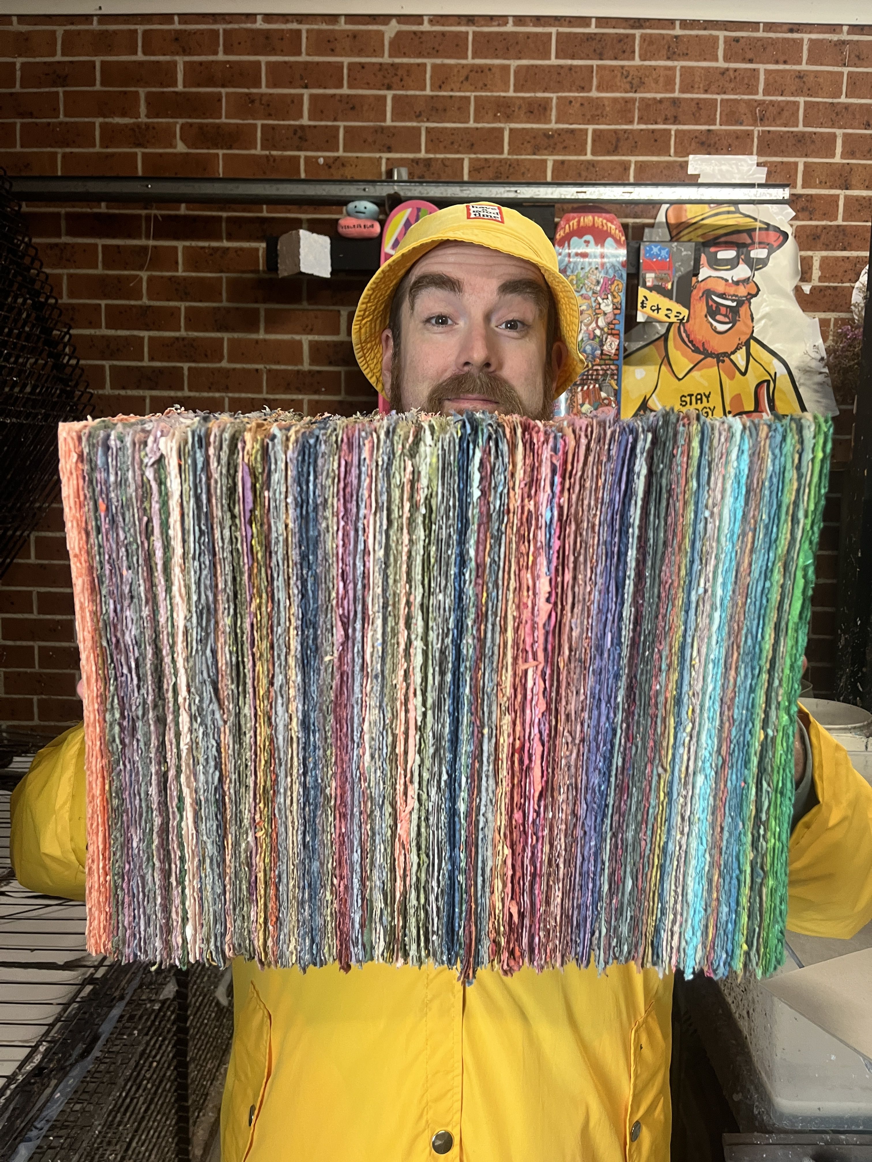 Roger holding up a large stack of colourful recycled paper showing off the raw edges
