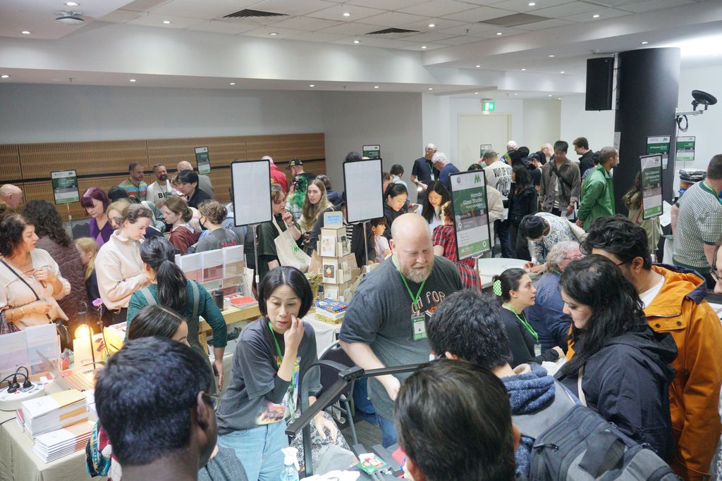 A crowd of visitors around the Hanabi Glass Studio table