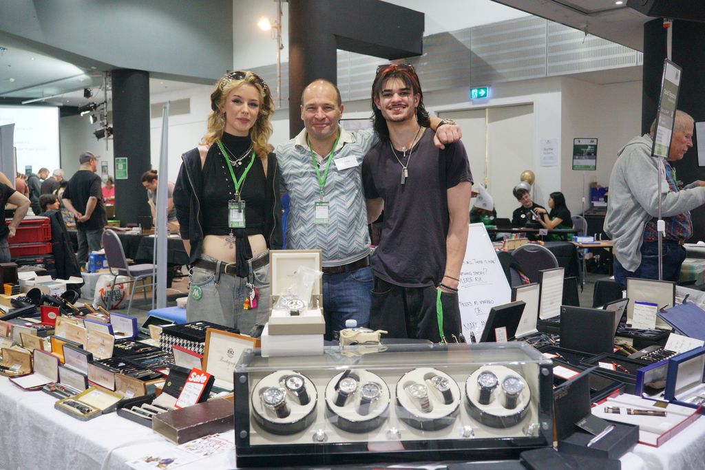 Three exhibitors posing together at their table