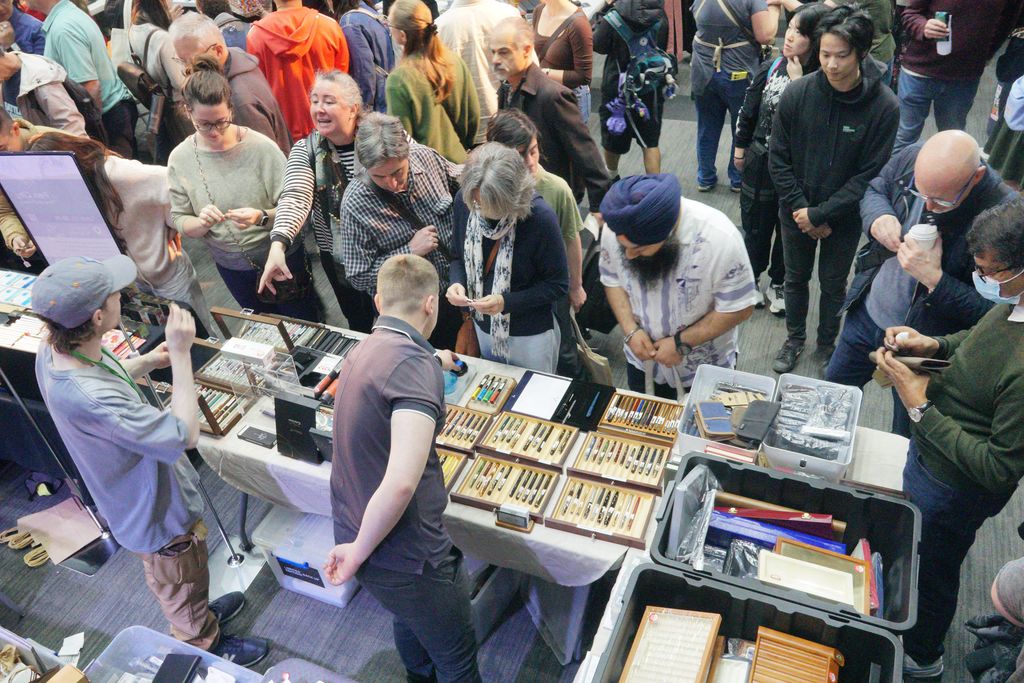 An exhibitor table seen from above, with a crowd of visitors