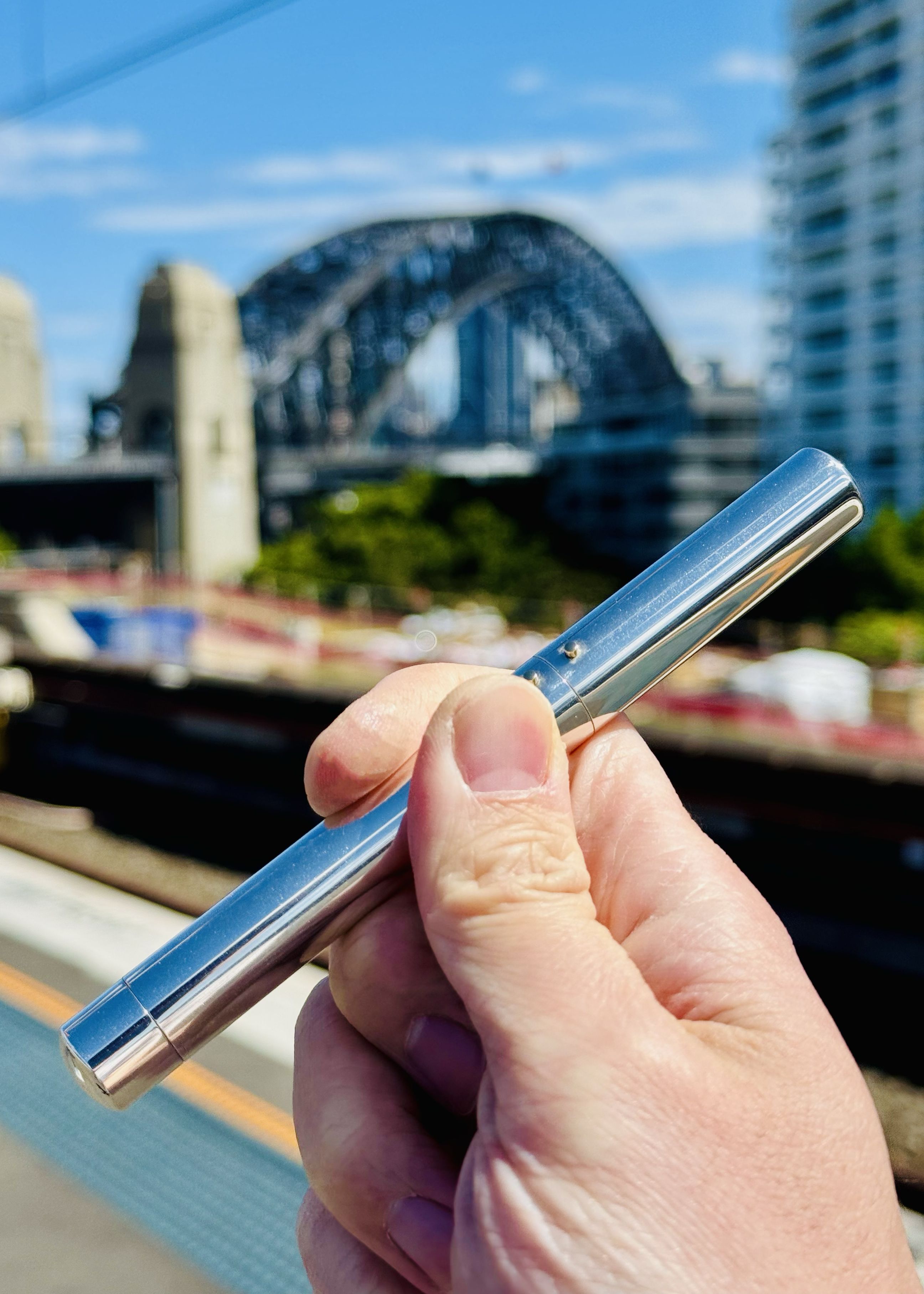 Chris holding up a fountain pen with Sydney Harbour Bridge in the background