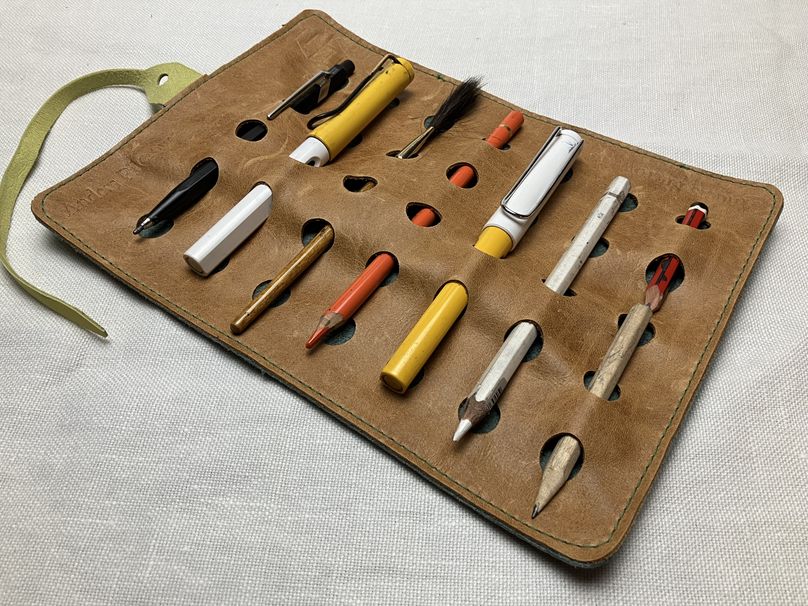 opened pen roll with pens and pencils in it