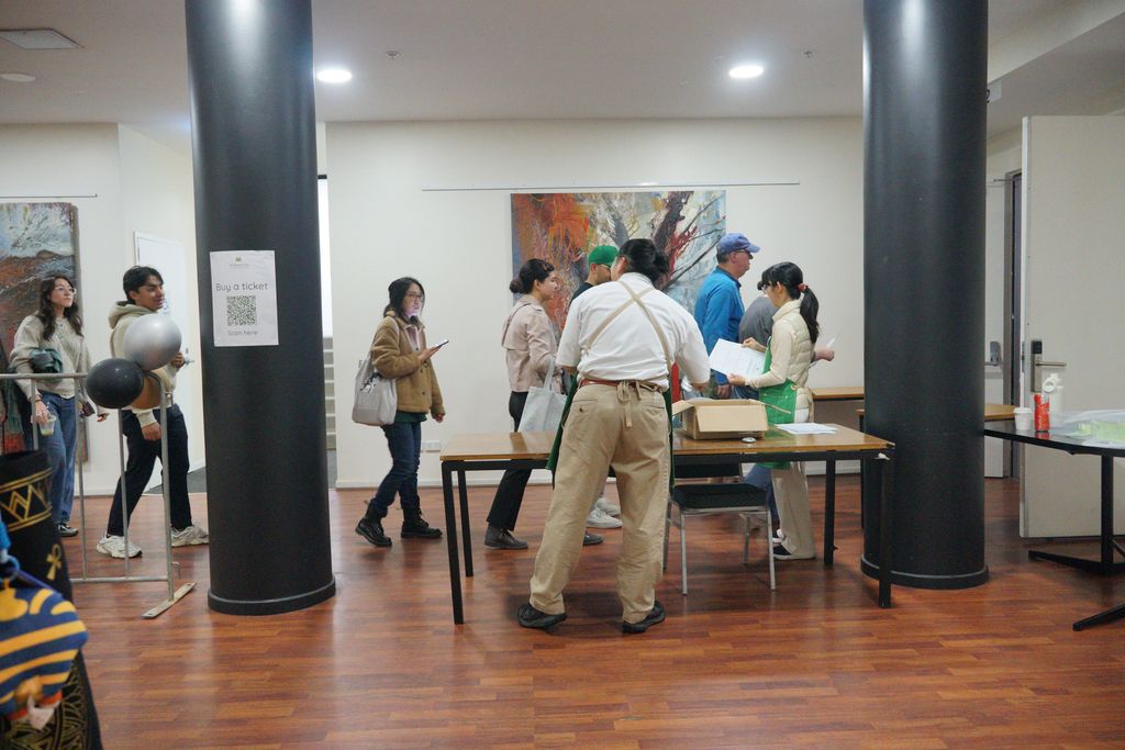 Volunteers welcome guests, handing out sheets of paper at a table in the foyer